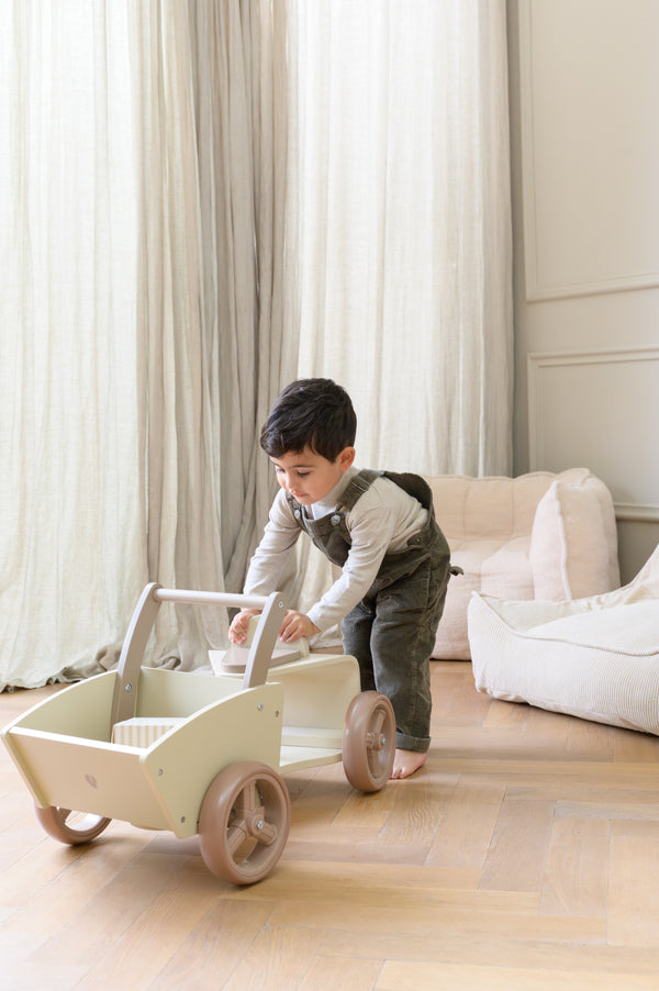 A young child playing indoors with the Babiem cargo bike Moos. The soft daylight, natural materials and neutral tones reflect Babiem’s focus on safe, imaginative and durable play.