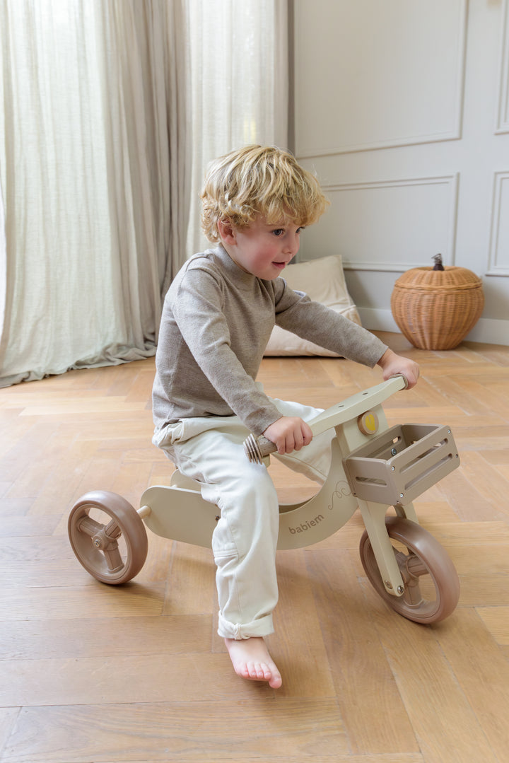 A young child riding the Babiem wooden balance bike James indoors. The soft daylight, warm wooden floor and neutral tones reflect Babiem’s natural, calm and durable design philosophy.