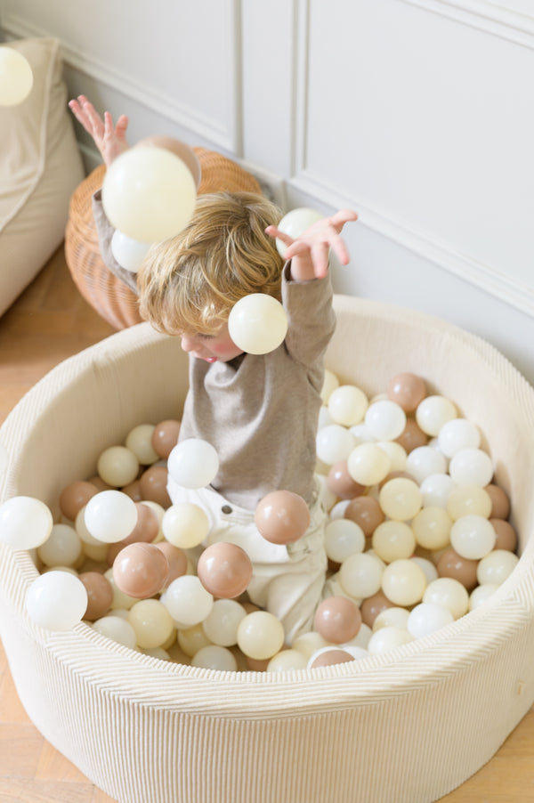 A child joyfully playing with soft-toned balls in the Babiem corduroy ball pit. The bright light and neutral setting capture Babiem’s warm, natural, and joyful approach to play.