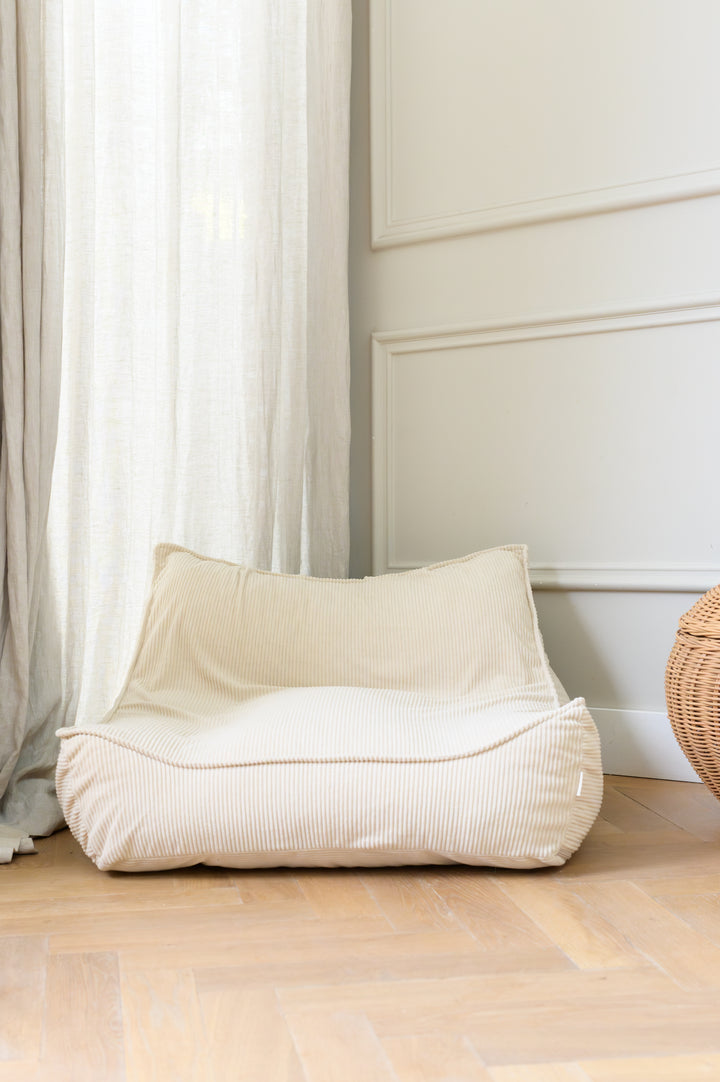 The Babiem beanbag Bruno displayed in a bright room with soft curtains and wooden flooring, showing its comfortable corduroy texture and relaxed shape.