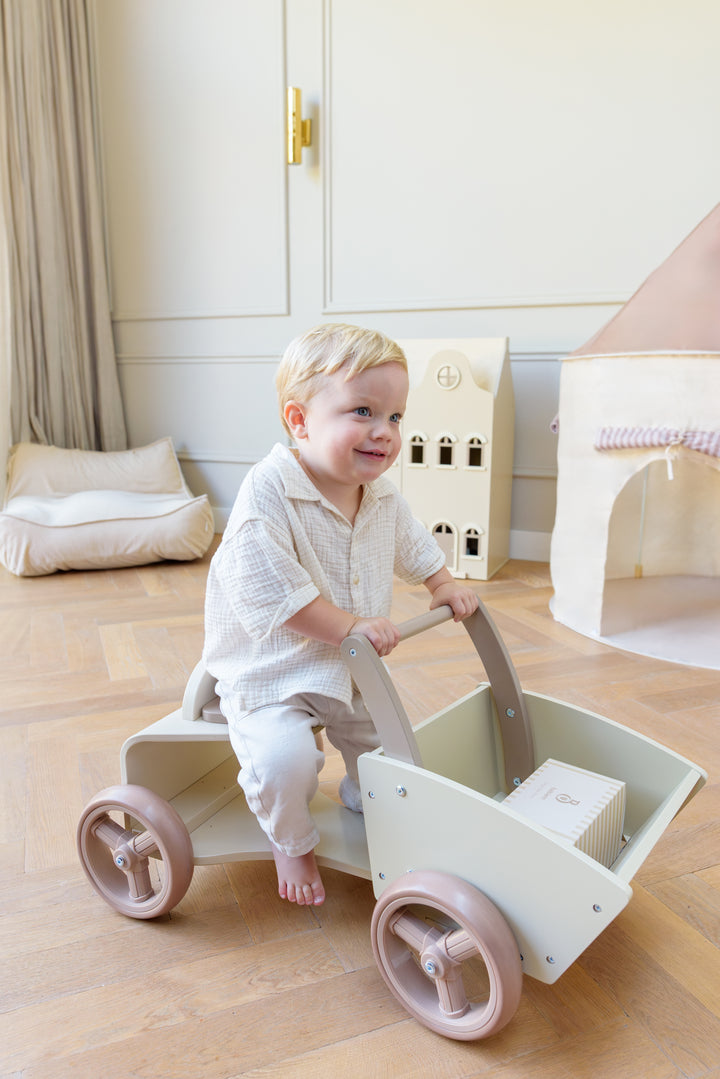 A smiling toddler riding the Babiem cargo bike Moos indoors. The soft natural light, warm tones and minimal decor reflect Babiem’s focus on safe, durable and joyful play.