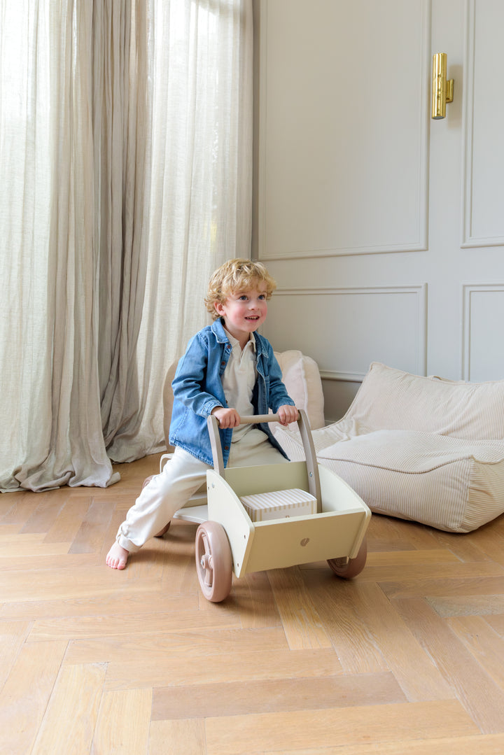 A child pushing the Babiem cargo bike Moos indoors, with a striped gift box placed in the cargo bike.
