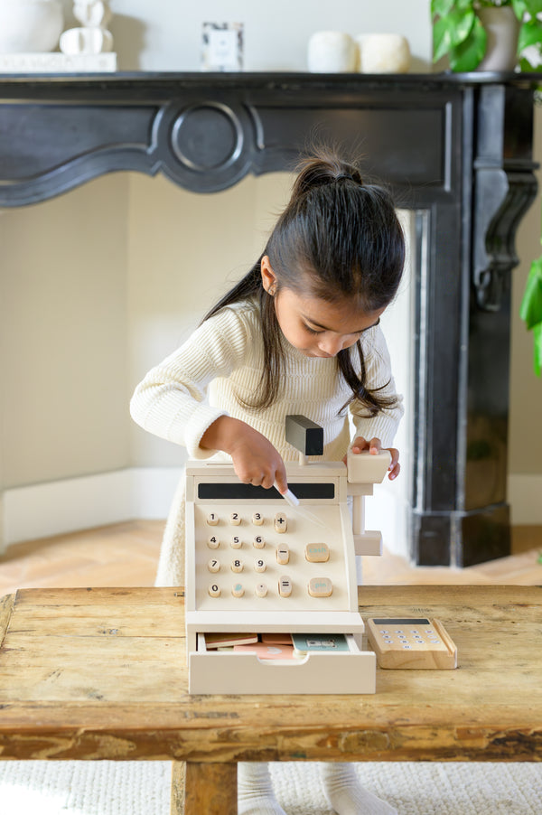 A young child playing with the Babiem cash register Coco, a wooden toy register designed to inspire imaginative and educational play.