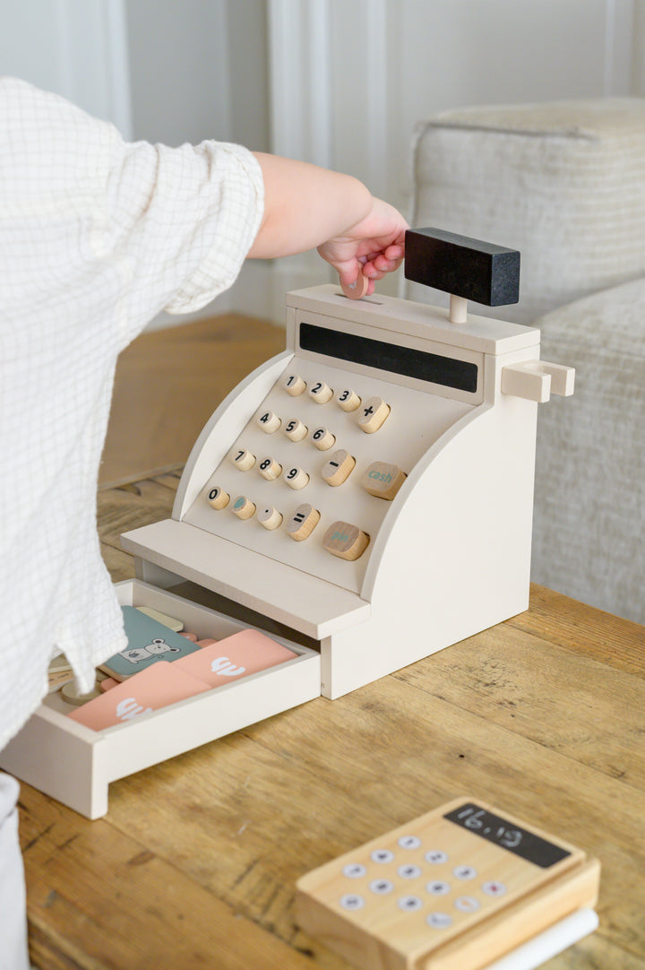 Child opening the drawer and handling wooden money on the Babiem cash register Coco