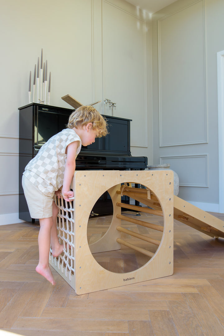 Child climbing on the Babiem wooden climbing cube with rope net.
