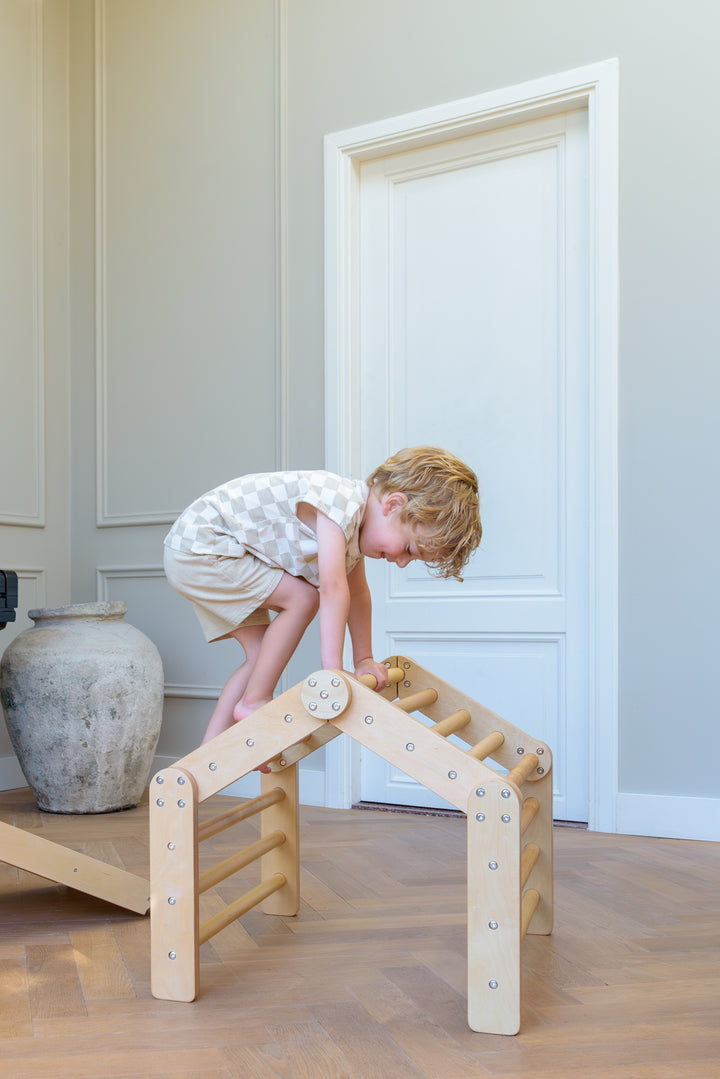 A young child climbs on Babiem's climbing house Ben indoors, exploring balance and coordination in a safe and playful way.
