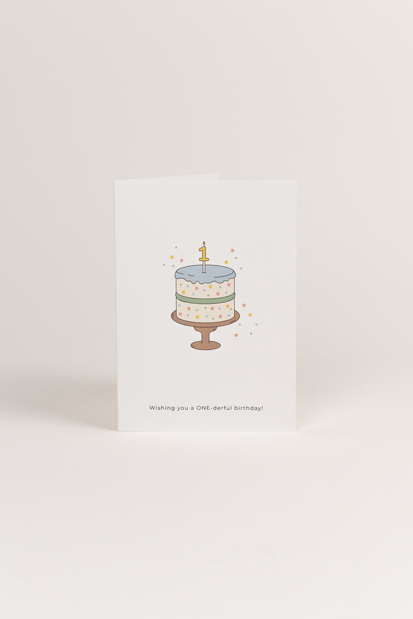 A white Babiem greeting card featuring a pastel-colored birthday cake with a number “1” candle on top and confetti surrounding it. The text “Wishing you a ONE-derful birthday!” is printed below the illustration.