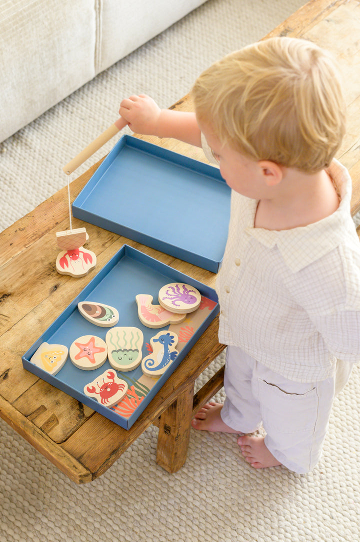 Toddler using magnetic fishing rod to catch wooden sea animals from Babiem fishing game Emma