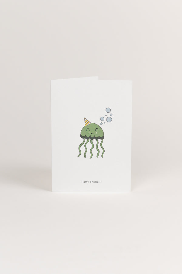 A white Babiem greeting card featuring a cute green jellyfish illustration wearing a striped party hat and surrounded by bubbles. The card has the text “Party animal!” printed below the design.