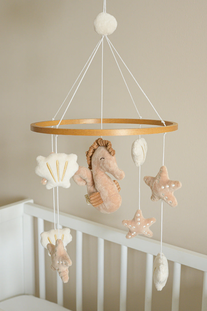 Babiem musical mobile Zoë with a seahorse, seashells, and starfish, gently swaying above a crib.