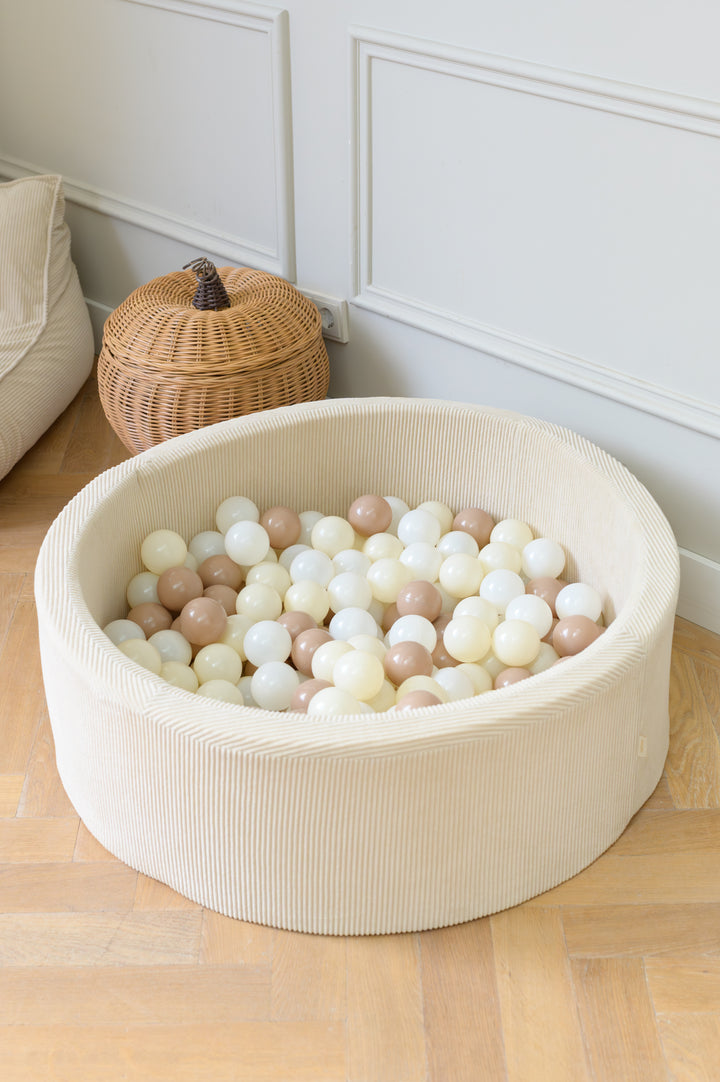 A beige corduroy Babiem ball pit filled with neutral-colored balls in white, cream, and taupe tones. The calm interior and natural materials reflect Babiem’s focus on timeless design, quality, and playfulness.