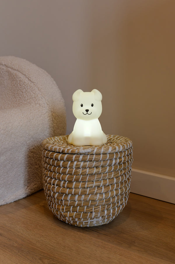 A soft glowing dog-shaped nightlight called Babiem Bibi, placed on a woven basket in a cozy children’s room.