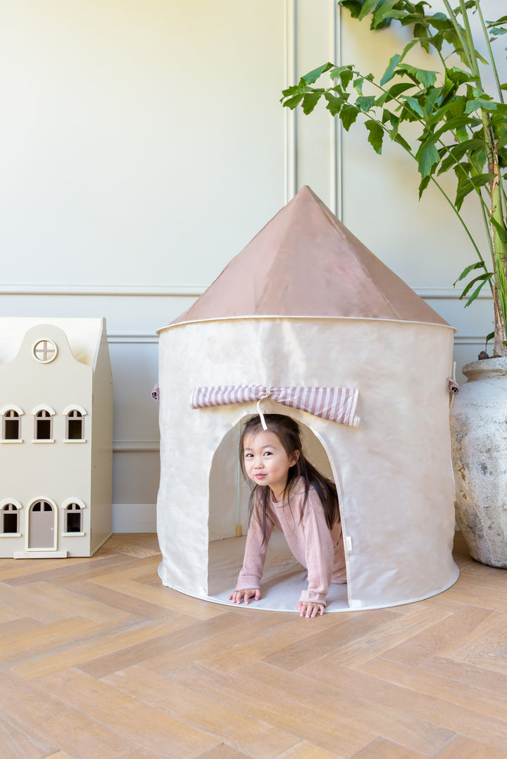 A child crawling inside the Babiem play tent Alice, set up in a bright room with wooden flooring and the Babiem dollhouse Lynn nearby.