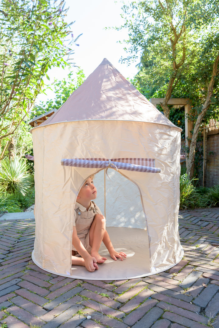 A young child sits inside the Babiem play tent Omar in a garden, looking up with curiosity while enjoying a cozy and playful outdoor setting.