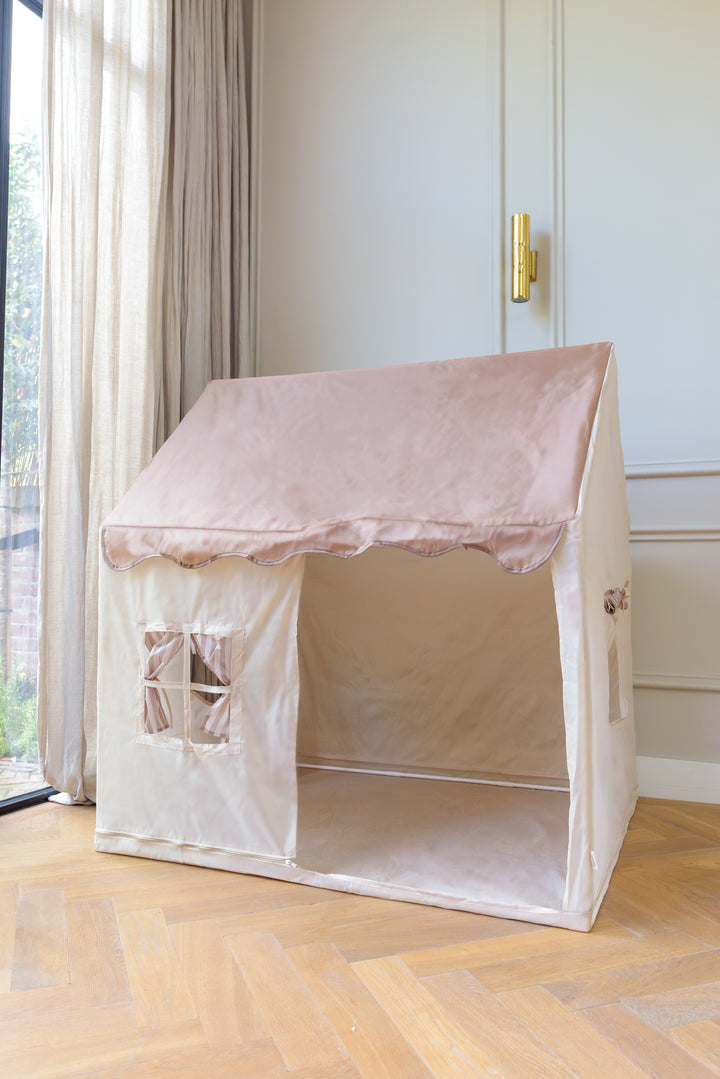 Babiem play tent Omar with a beige fabric base and taupe pink roof, featuring small window openings with curtains, placed in a softly lit room with wooden flooring and neutral decor.