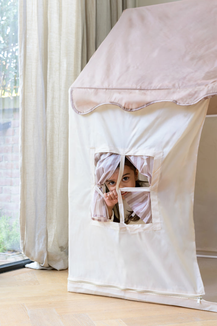 A child peeking through the striped fabric window of the Babiem play tent Omar.