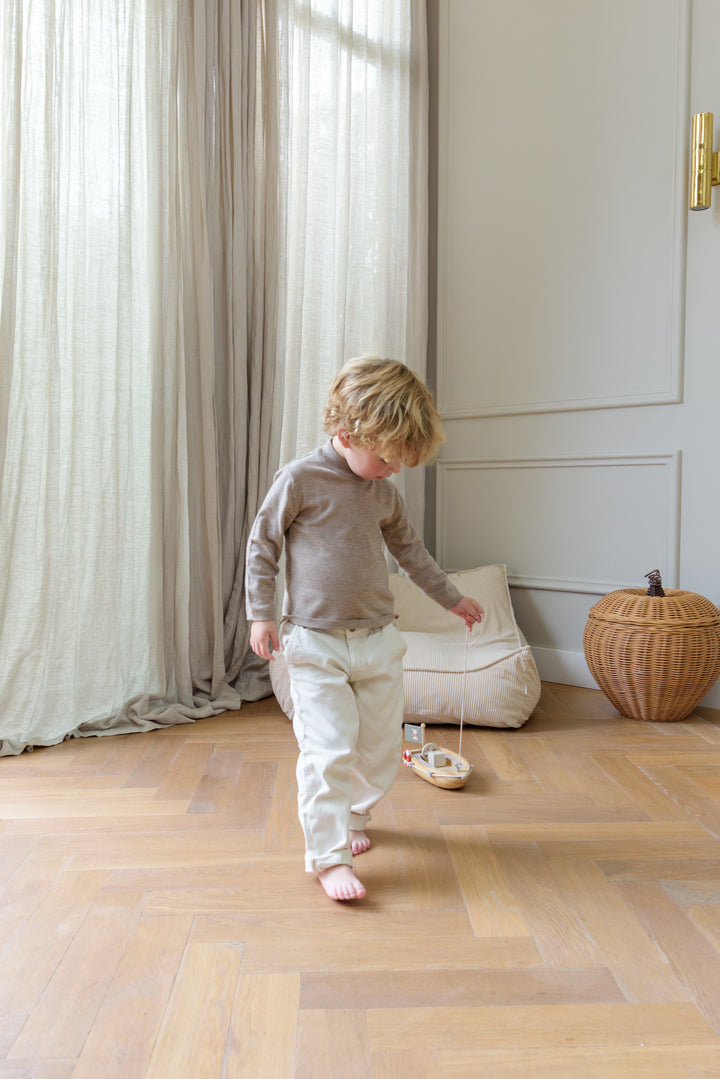 A young child playing with the Babiem pull-along Xavier, a wooden pull toy designed to encourage movement and imaginative play.