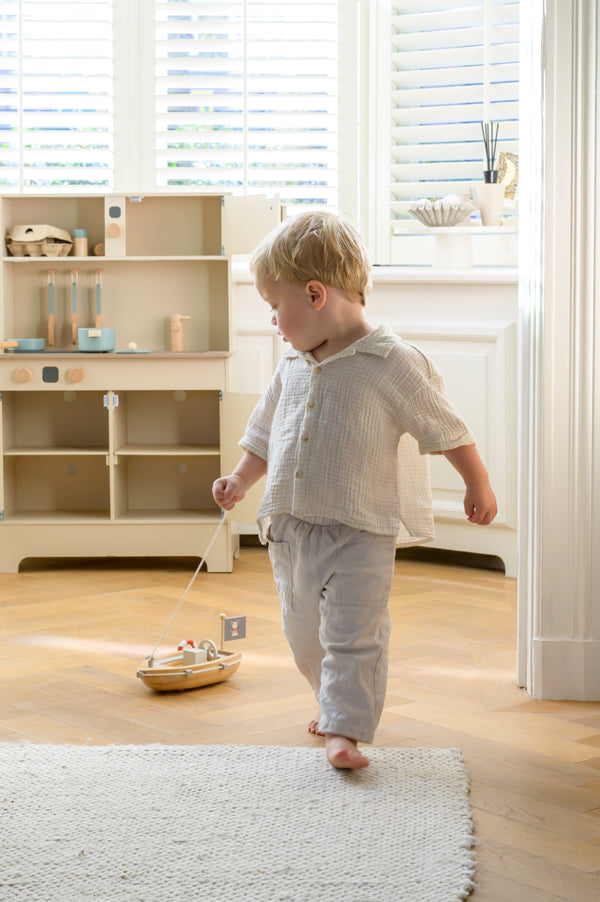 Toddler walking and pulling the Babiem pull-along boat Xavier across the floor