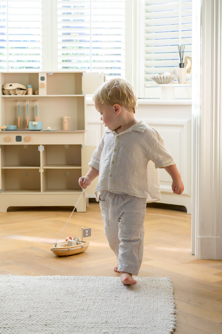 Toddler walking and pulling the Babiem pull-along boat Xavier across the floor