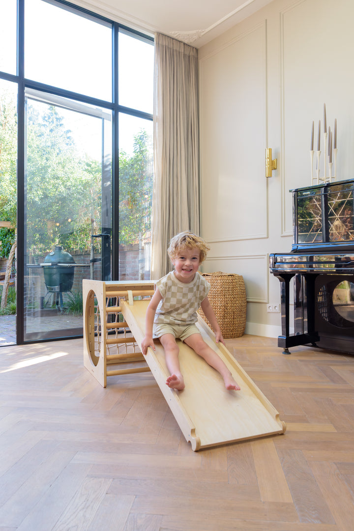 Toddler sliding on the Babiem slide Ben, a safe climbing ramp that sparks movement and joy.