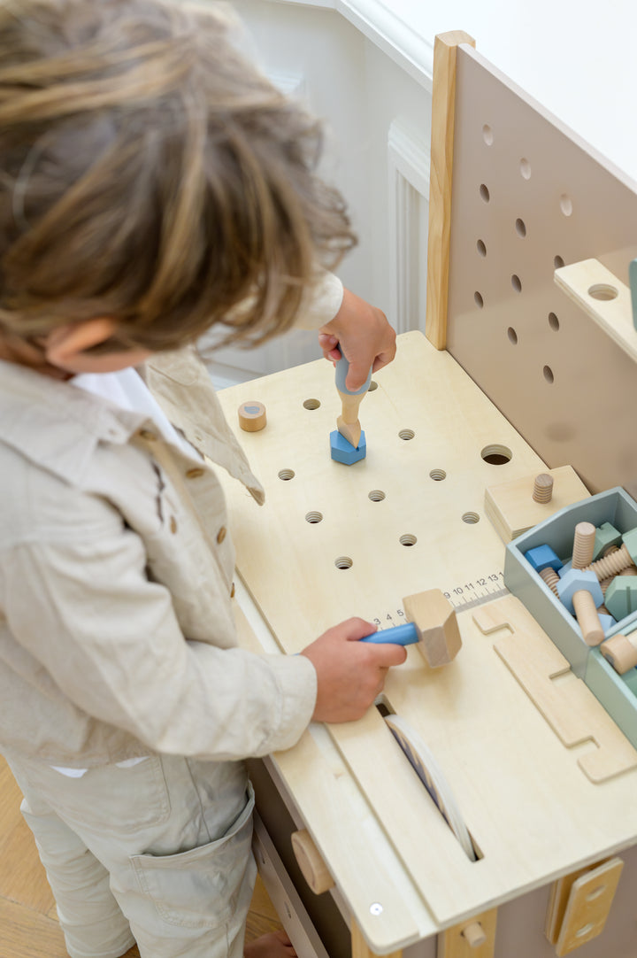 A child using the hammer and screwdriver on the Babiem tool bench Thomas, placing wooden shapes into the worktop holes.