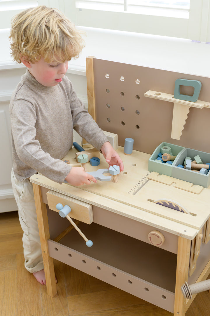 Child practicing fine motor skills using wooden wrench and bolts on the Babiem toolbench Thomas