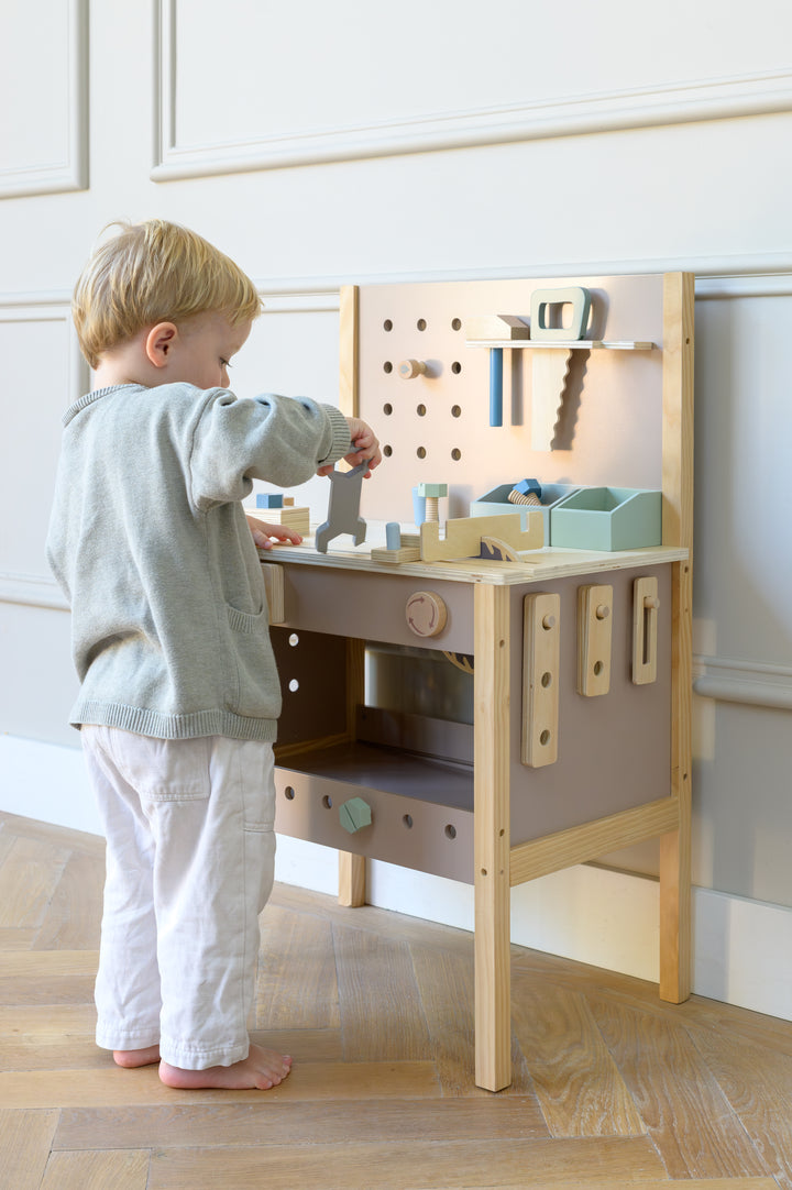 Young child playing with the wooden toolbench Thomas and tools