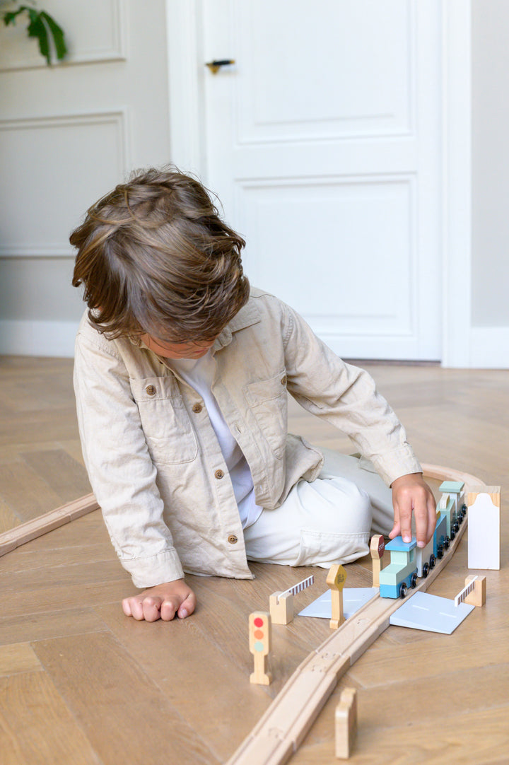 Child sitting on floor playing with Babiem train set Felix wooden train and traffic signs