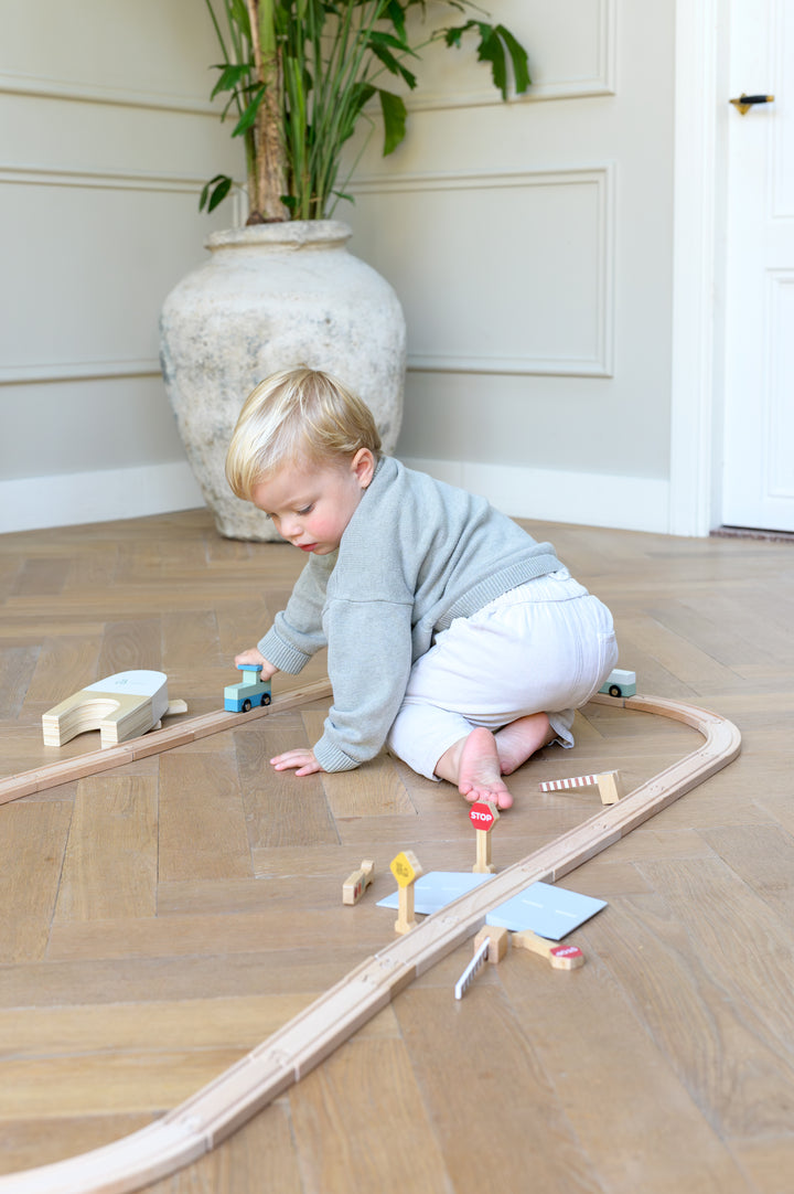 Toddler driving wooden train on Babiem train set Felix track with stop sign and railway crossing