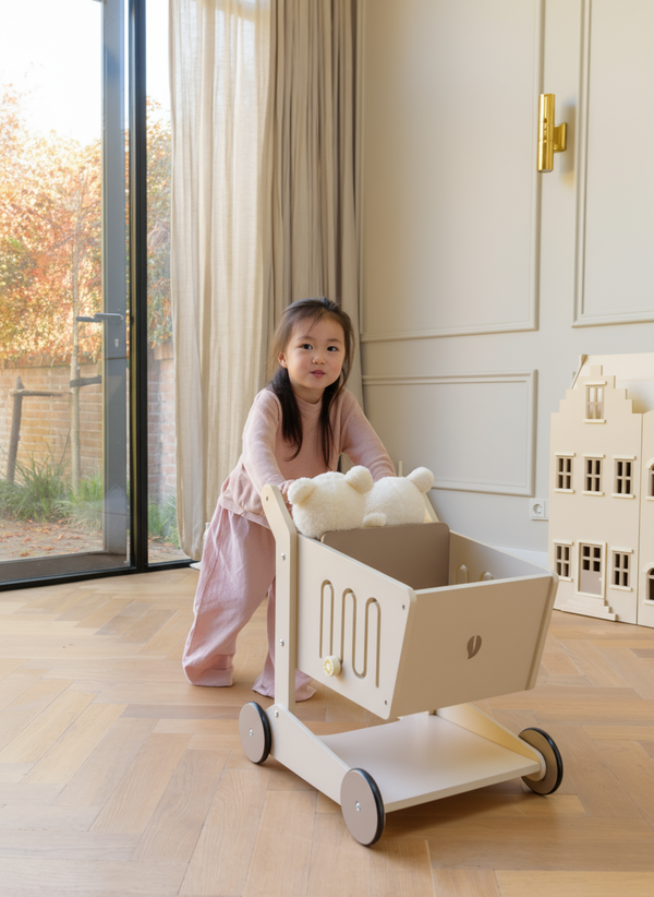 A young child playing indoors with the Babiem wooden shopping cart Oliver filled with soft toys. The scene features natural light, soft tones, and a calm, minimalist interior that reflects Babiem’s timeless and durable design style.