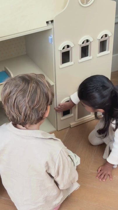 Two children playing with the Babiem Lynn wooden dollhouse, inspired by the Dutch canal houses. At times the girl plays independently, carefully arranging the miniature furniture, while the boy also explores the rooms. In other moments they play together, interacting with the dollhouse, its accessories and each other in a gentle, playful way.