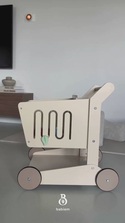 An unboxing video of the Babiem shopping cart Oliver, showing the different parts being unpacked and assembled. A mother and child are assembling the shopping cart. At moments, her child appears in the frame, curiously watching  the shopping cart come together.